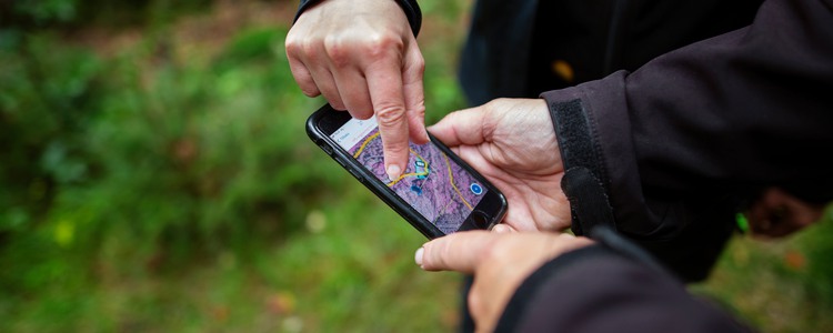 Närbild på en mobiltelefon där två personer pekar och tittar på ett kartprogram. Foto: Jenny Leyman