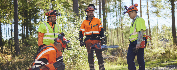 Utbildningsgrupp i skyddskläder står samlad runt en motorsåg. Foto: Patrik Svedberg