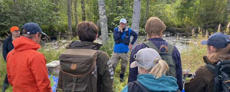 Grupp av studenter på fältexkursion vid vattendrag. Foto: Lennart Täljeblad