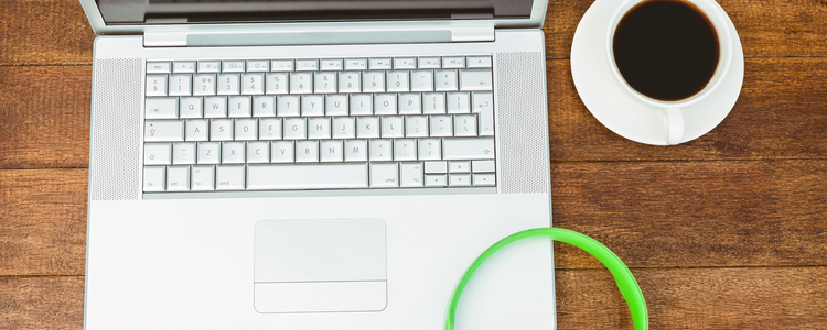 View of a grey laptop with a green headphone on wood desk