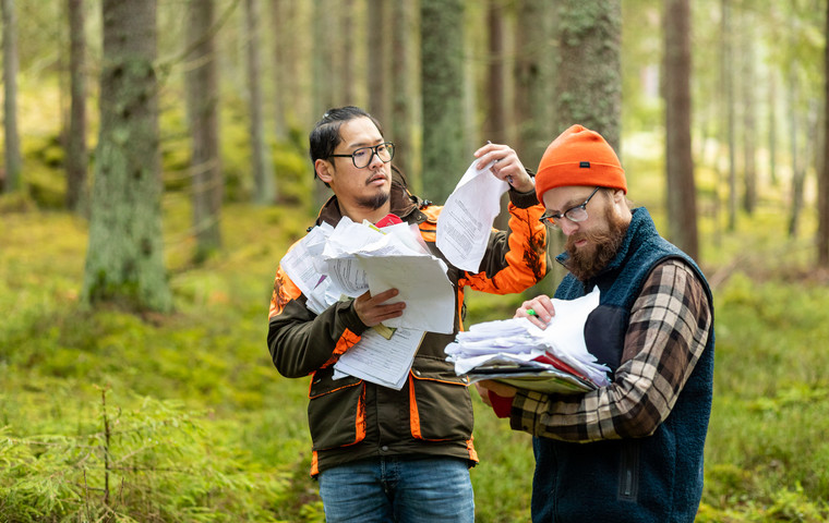 Två män som står med massa anmälningsblanketter mitt i skogen. Foto: Bulldozer