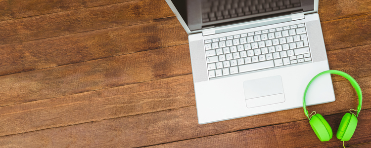 View of a grey laptop with a green headphone on wood desk