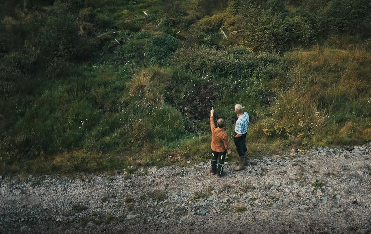 Två personer pekar på ett grönt markområde.