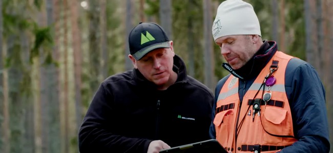 Två män tittar på digital skärm i skogen