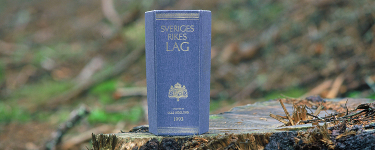 Den svenska lagboken på en stubbe i skogen.