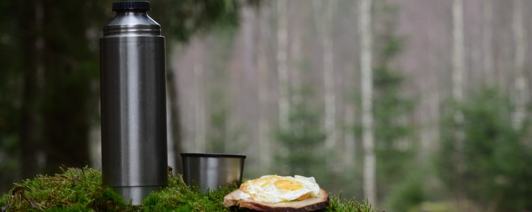 Termos och äggmacka på stubbe i skogen.