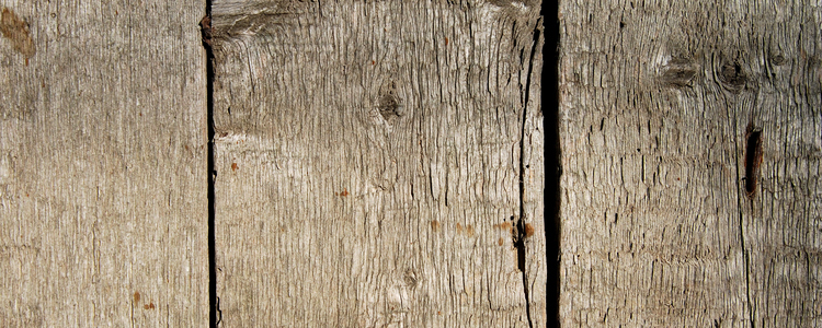 Gråfärgad plank på husvägg.