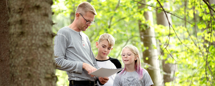 Pappa o två barn tittar i skogsbruksplanen.  Foto: Camilla Zilo